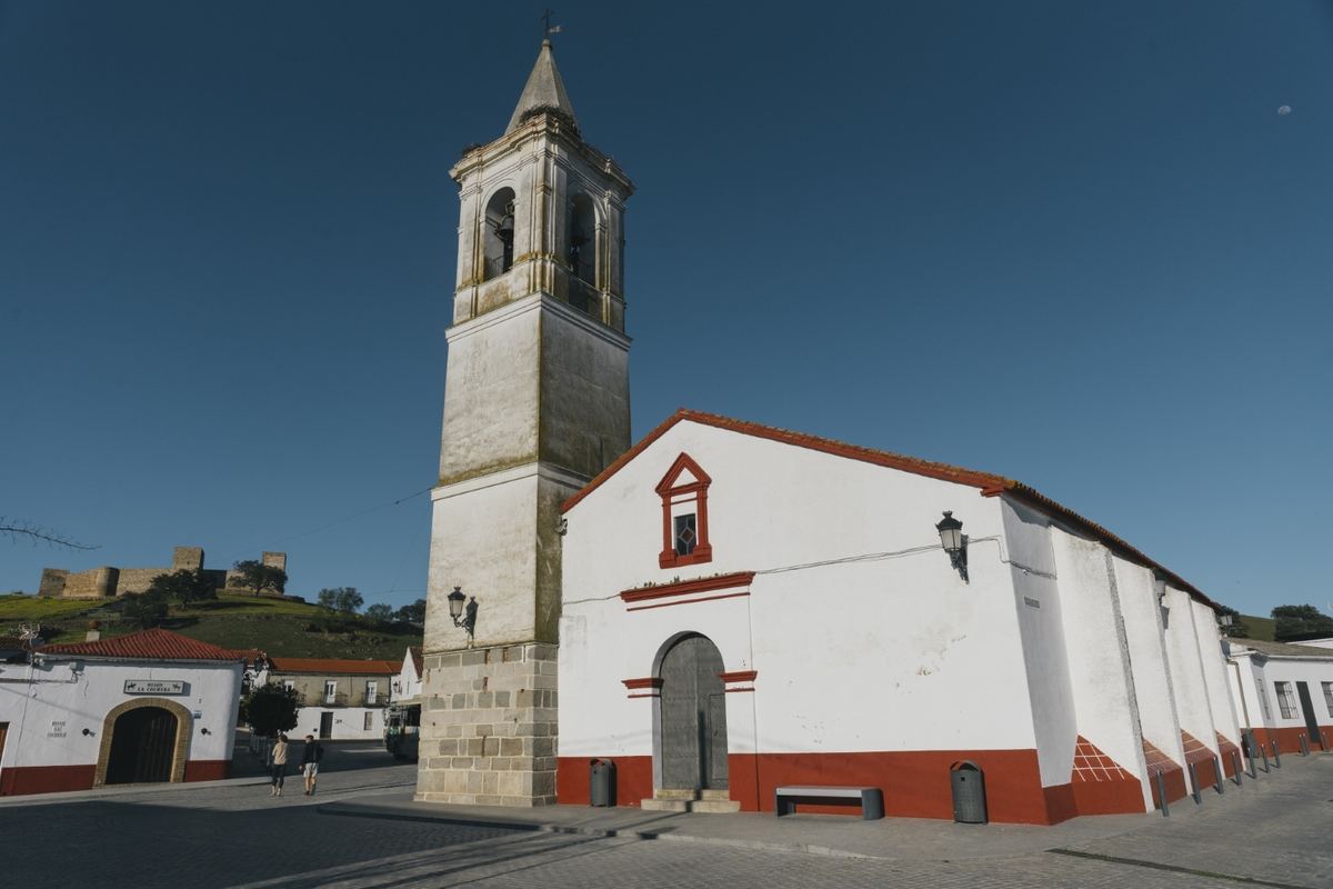 Iglesia de San Bartolomé en El Real de la Jara, con el castillo al fondo sobre la colina